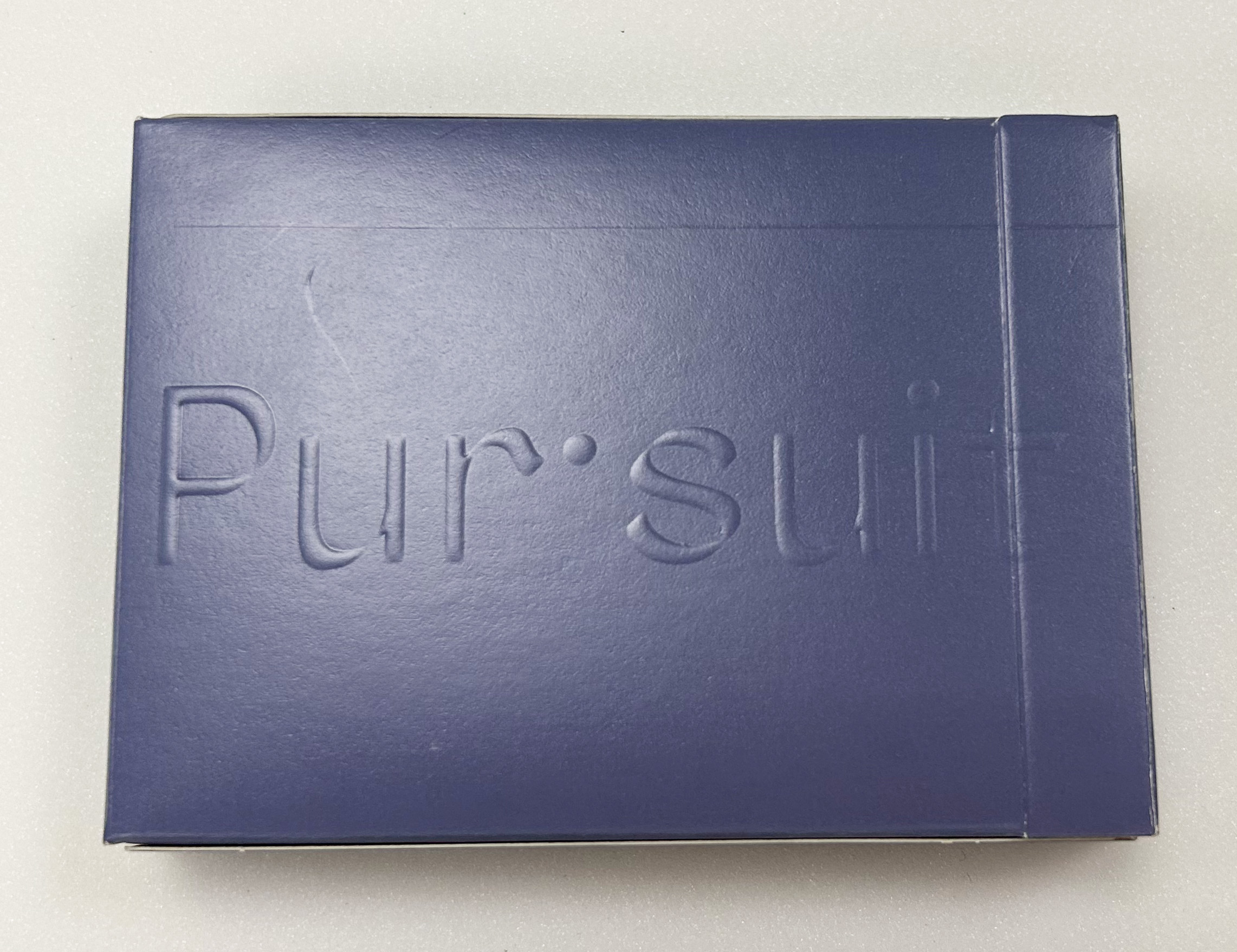 An embossed text, reading "Pur·suit" on a navy blue box. 