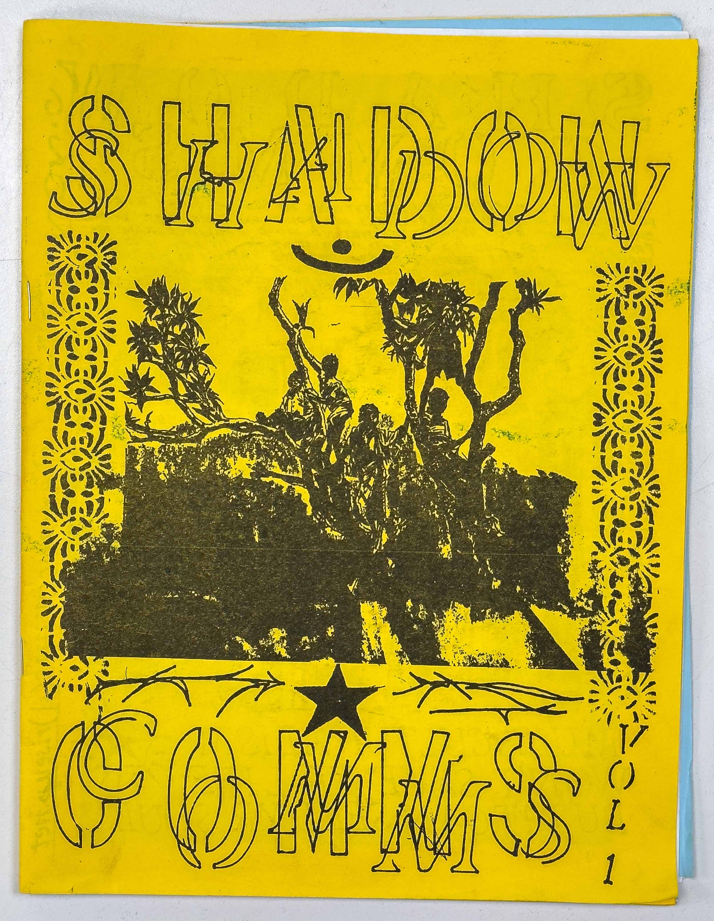 a black print on a yellow background of boys climbing on trees, along with a black overlapping shadow