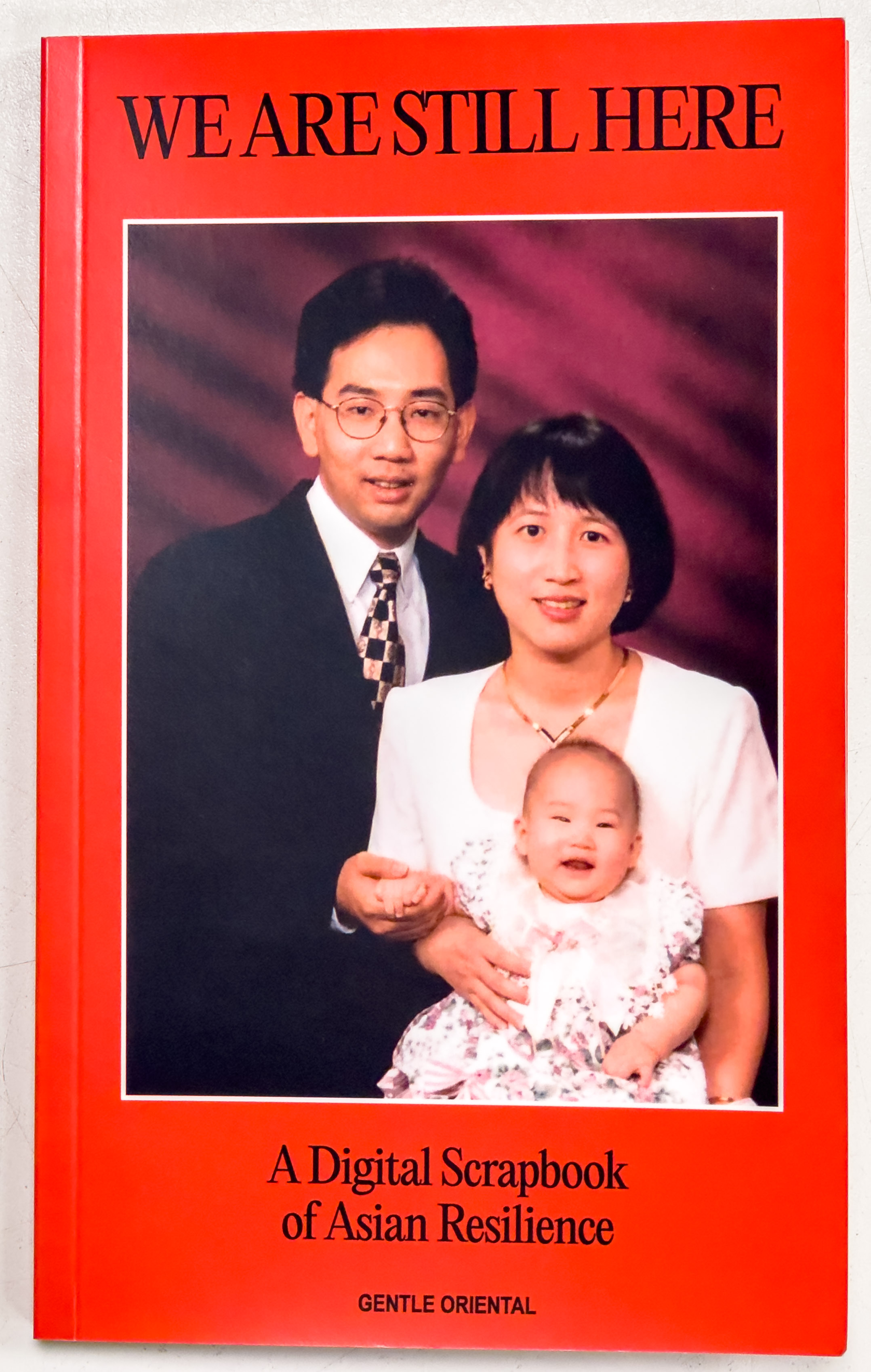 Red cover with black text of title along with a colored photograph of two Asian parents and their baby.