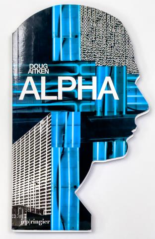 The cover is the shape of a man's side profile of his head and neck, with images of a black anf white building, neon blue lights, and white numbers. Along with white text reading, "Doug Aitken, Alpha" towards the top, and JRP/Ringier at the bottom. 