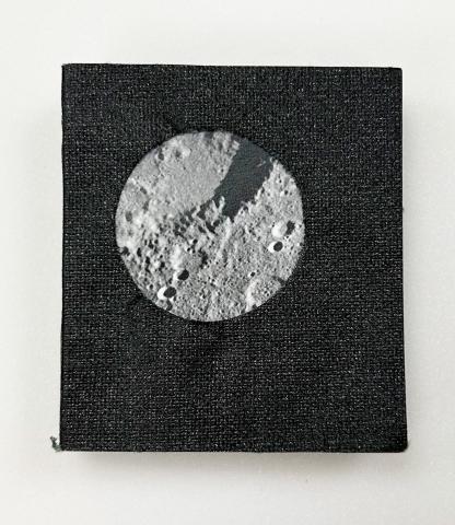 A black vegan leather cover with an image of the moon's lunar surface is in the center. 